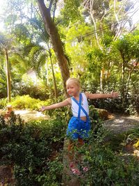 Girl standing by plants against trees