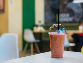 A plastic cup with a smoothie stands in a cafe