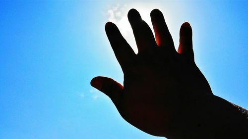 Low angle view of cropped hand against clear sky