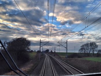 Railroad tracks against cloudy sky