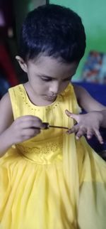 Close-up of baby boy holding yellow indoors