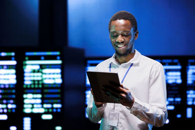 Portrait of young man using digital tablet while standing in office