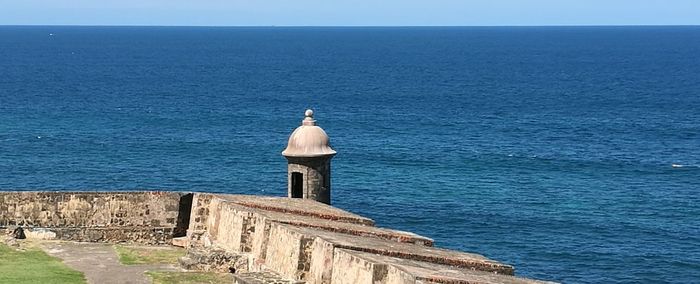 Rear view of man standing on cliff in front of sea