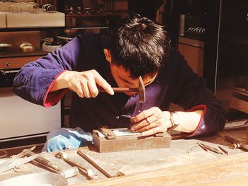 Man holding hammer over nail at workshop