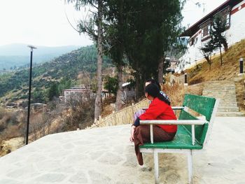 Full length of woman sitting on railing