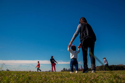 Family on field against clear blue sky