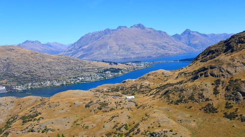 Scenic view of lake and mountains against clear blue sky