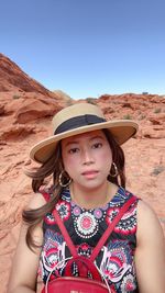 Portrait of woman wearing hat standing at desert against clear sky