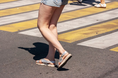 Low section of woman walking on road