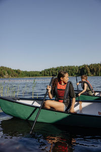 Girl looking away while sitting in kayak on lake at summer camp