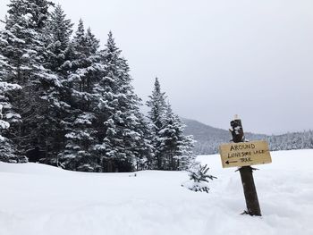 Information sign on snow covered landscape against sky