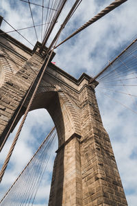 Low angle view of suspension bridge against cloudy sky