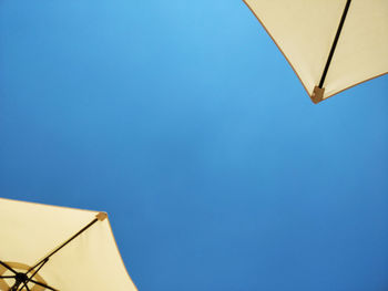 Low angle view of umbrella against clear blue sky