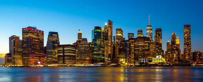 Illuminated modern buildings in city against sky