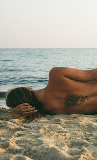 Low section of woman relaxing at beach
