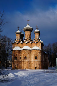 Church by building against sky during winter