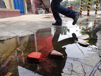 Low section of man reflection in puddle