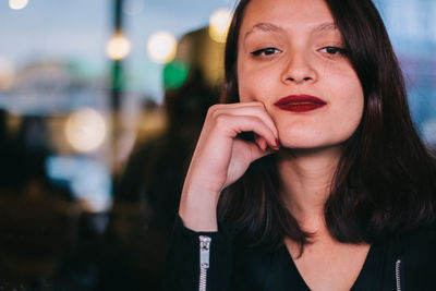 Close-up of young woman touching cheek sitting at restaurant