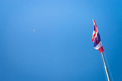 Low angle view of flags against clear blue sky