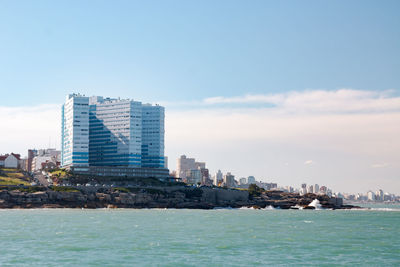 Sea by buildings against sky in city