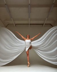 Full length of young woman jumping against wall