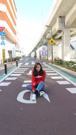 Portrait of young woman sitting on road