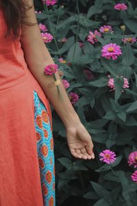 Midsection of woman standing by pink flowering plants