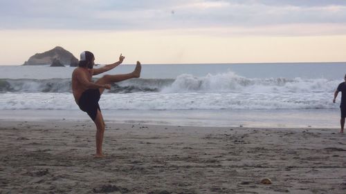 Full length of man on beach against sky during sunset