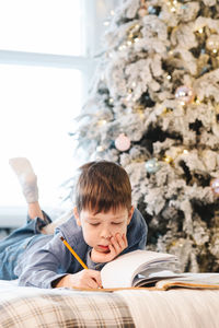 Side view of boy sitting on bed at home