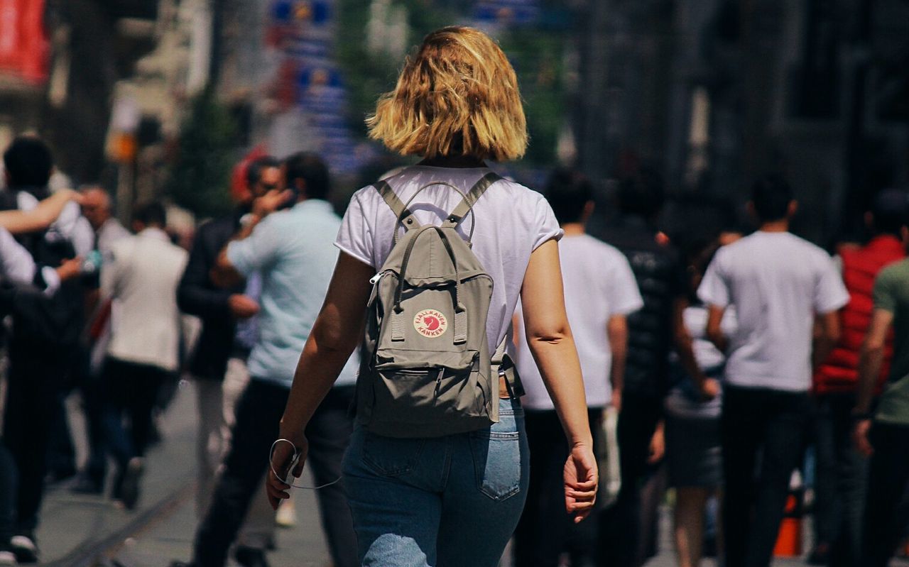 rear view, city, real people, lifestyles, three quarter length, women, hair, street, walking, city life, one person, hairstyle, focus on foreground, adult, leisure activity, incidental people, casual clothing, architecture, standing