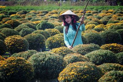 Smiling woman wearing conical hat working at flower field