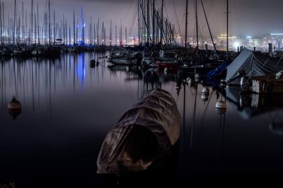 Sailboats moored in harbor at night