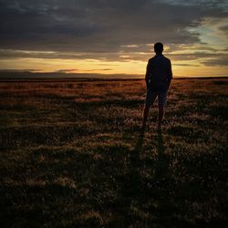 Silhouette of people standing on field at sunset