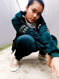 Portrait of girl sitting against wall