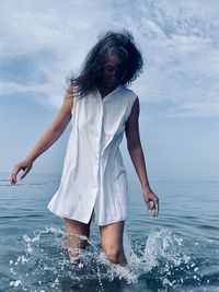 Girl is standing in the sea in the spray of drops