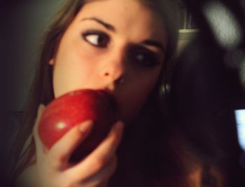 Close-up portrait of young woman holding apple
