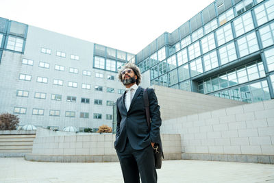 Portrait of businessman standing against building