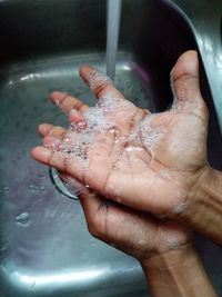 Cropped image of hand touching water in bathroom