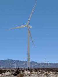 Windmill on field against clear blue sky