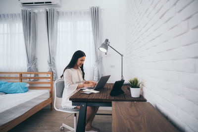 Young woman using mobile phone while sitting on table