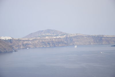 Scenic view of sea by mountain against clear sky