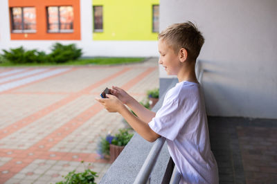 A child holds a phone in his hands near the school