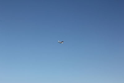 Low angle view of airplane against clear blue sky