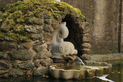 Statue on rock by water