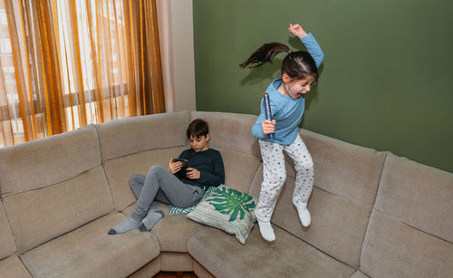 Full length of girl jumping on sofa at home