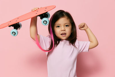 Portrait of cute girl standing against pink background