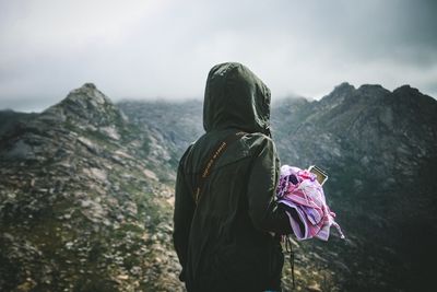 Rear view of man standing on mountain against sky