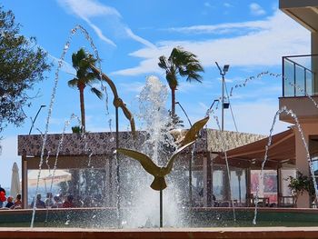 View of palm trees and fountain against sky