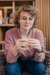 Smiling woman holding coffee cup sitting at cafe
