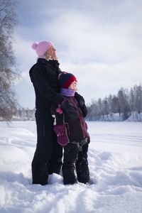 Father and son on field during winter against sky